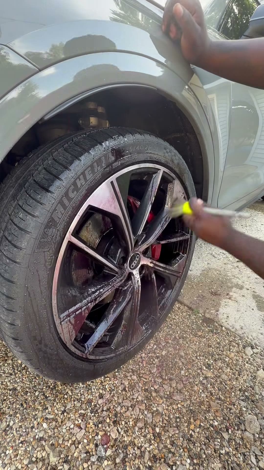 Brush working through the spokes of a gray Audi SUV wheel