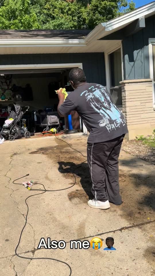 Detailer working beside a vehicle in a customer driveway
