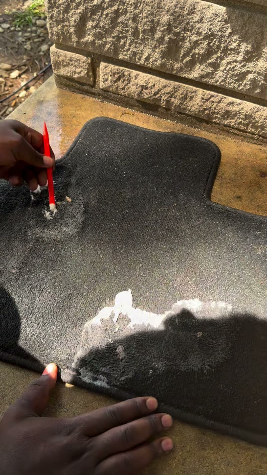 Cleaning solution being applied to spots on a vehicle floor mat